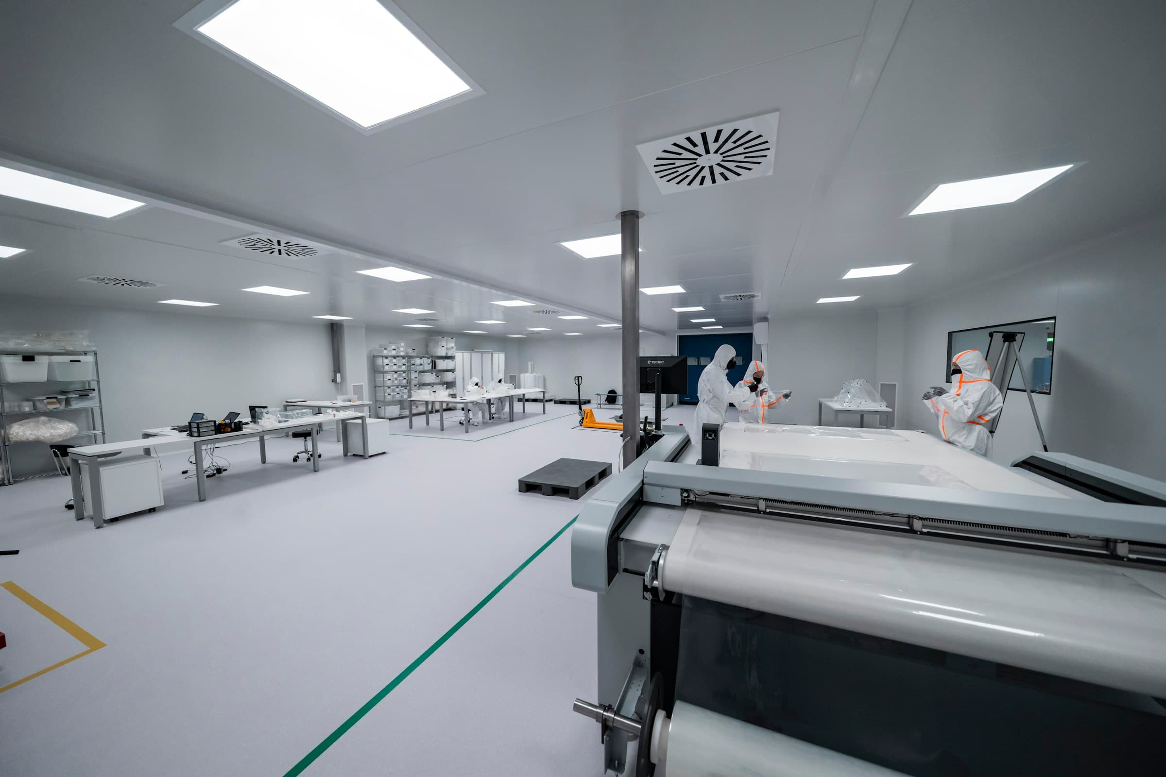 Modern sterile pharmaceutical cleanroom with workers in PPE